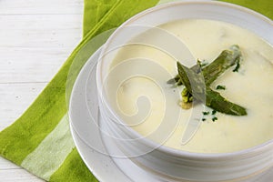 White asparagus cream soup with green asparagus heads garnish in