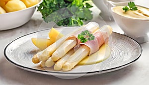 White asparagus with ham, hollandaise sauce and potatoes on the plate