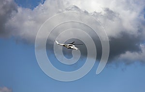 White attack helicopter of the United Nations peacekeeping mission in flight against the background of dark cloud