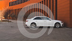 A white Audi A4 parked under an orange office building