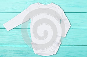 White baby mock up jumpsuit on blue wooden background. Baby bodysuit mockup and template blank copy space. Top Front view.