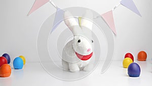 White baby rabbit toy with easter colorful eggs