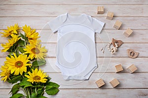 White baby short sleeve bodysuit mockup with yellow sunflowers, wooden toy