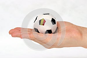 On white backgrouMini football in hand and one black point of football is Belgium flag