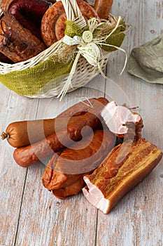 On a white background, a basket with meat delicacies. Smoked meats and sausages. Ham,gammon, pork loin, homestyle