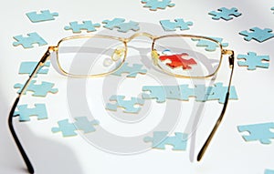 On a white background blue puzzles. A red puzzle is visible through the lens of the glasses.