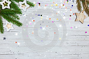 White background with colorful festive confetti, christmas tree branch and glowing lights