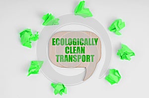 On a white background, crumpled green leaves and a wooden sign with the inscription Environmentally friendly transport