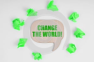 On a white background, crumpled green papers and a wooden sign with the inscription - Change The World