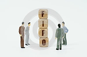 On a white background, figures of businessmen and wooden cubes with the inscription - FIFO