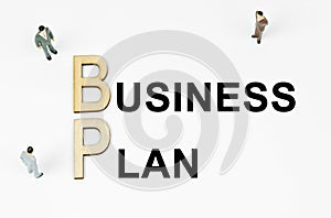 On a white background, figures of businessmen, wooden letters and the inscription - BUSINESS PLAN