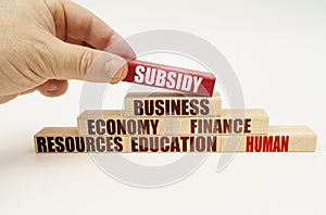 On a white background, the hand adds blocks with inscriptions on a red block, the inscription - SUBSIDY