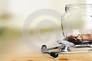 Money Jar with coins and stethoscope, close-up