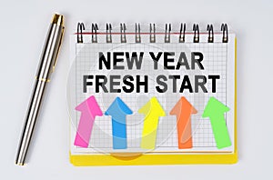 On a white background lie a pen and a notebook with the inscription - NEW YEAR FRESH START