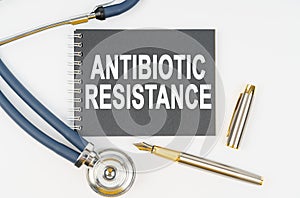 On a white background lie a stethoscope, a pen and a notebook with the inscription - ANTIBIOTIC RESISTANCE