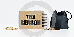 On a white background lies a bag with money, coins and a notebook with the inscription - TAX SEASON