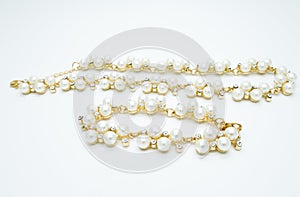 On a white background lies a pearl necklace on the neck and bracelet