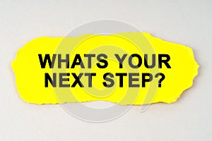 On a white background lies yellow paper with the inscription - WHATS YOUR NEXT STEP