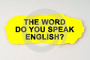 On a white background lies yellow paper with the inscription - THE WORD DO YOU SPEAK ENGLISH