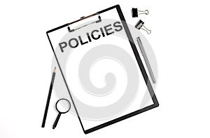 On a white background magnifier, a pen and a sheet of paper with the text POLICIES . Business concept