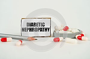 On a white background, medical capsules, a pencil and a cardboard plate with the inscription - Diabetic nephropathy