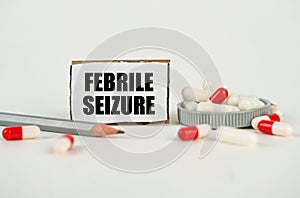 On a white background, medical capsules, a pencil and a cardboard plate with the inscription - FEBRILE SEIZURE