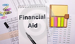 On a white background near bright papers is written Financial aid. financial concept