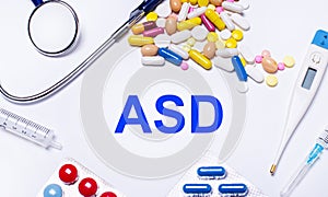 On a white background pills, stethoscope, syringe, thermometer and text ASD Autism Spectrum Disorder. Medical concept