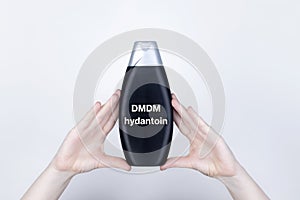 Chemical components on the shampoo label: DMDM hydantoin. Female hands hold the jar on which indicates the harmful ingredient. photo