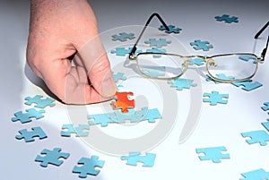 On a white background puzzles inside out. One red puzzle is held by female fingers