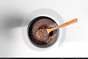 On a white background quinoa grain red, lie in a black bowl