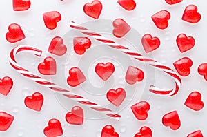 White background with red hearts pattern and candy canes, flat lay