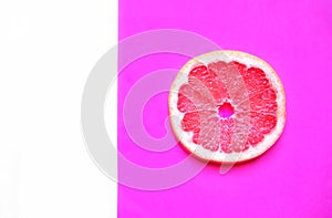 White background and a round pink grapefruit cut against a purple background, minimalism, close-up, selective focus, copy space