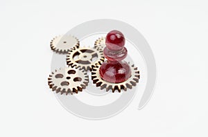 On a white background, there are wooden gears on which a pawn stands