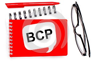 On a white background, white and red notepads, black glasses, a red pen and a white card with the text BCP Business Continuity