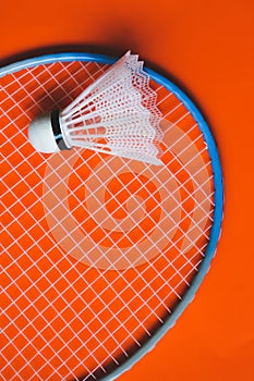 White badminton shuttlecock and racket on an orange background.