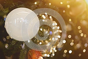 White ball hanging on pine branches, christmas garland and decorations on abstract bokeh background