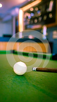 White ball and stick on billiard table with blurred background