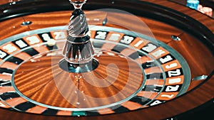 White ball stopped in rotating casino roulette. Close up wooden roulette wheel