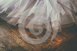 White ballet tutu on wooden floor. Retro filtered photo