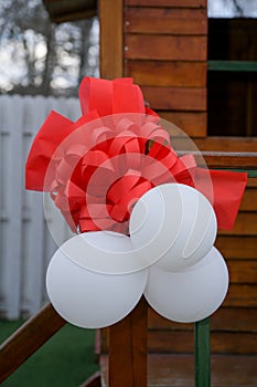 White balloons and red satin trousers, as a decoration on a wooden pillar