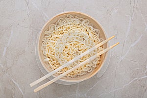 White bamboo plate bowl with egg noodles and chopsticks on a light background