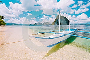 White banca island hopping boat at Las cabanas beach with amazing Pinagbuyutan island in background. Beautiful landscape