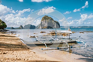 White banca island hopping boat at Las cabanas beach with amazing Pinagbuyutan island in background. El Nido, Palawan, Philippines