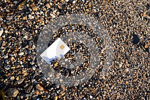 White Bank Card Lies On Sand And Pebble Beach On Sunset Moraitika, Corfu, Greece. The Concept Of Payment For Nature And Unlimited