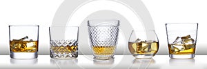 A white bar with a row of different style whisky glasses and ice, isolated on white