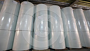 White barrels in the factory warehouse, white barrels stand in a row in the warehouse. Large white barrels in stock