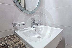 white basins in bathroom interior with granitic tiles
