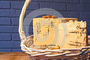 A white basket filled with various cheeses against a brick wall.