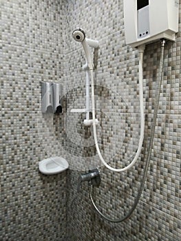 White bath hand shower fixture on the colorful warmtone wall with other items in modern bathroom